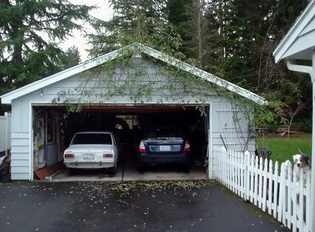 Detached two-car garage with the door open and two cars parked inside