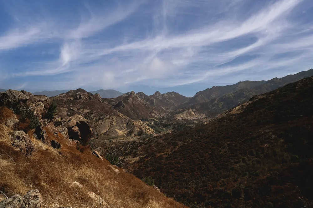 Rocky canyon walls and chaparral under long streaks of cloud